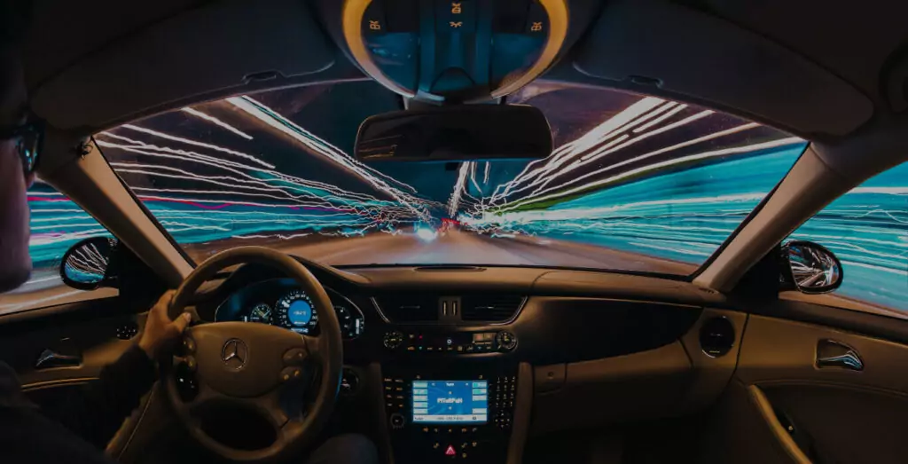 man driving car through tunnel with multi-color lights